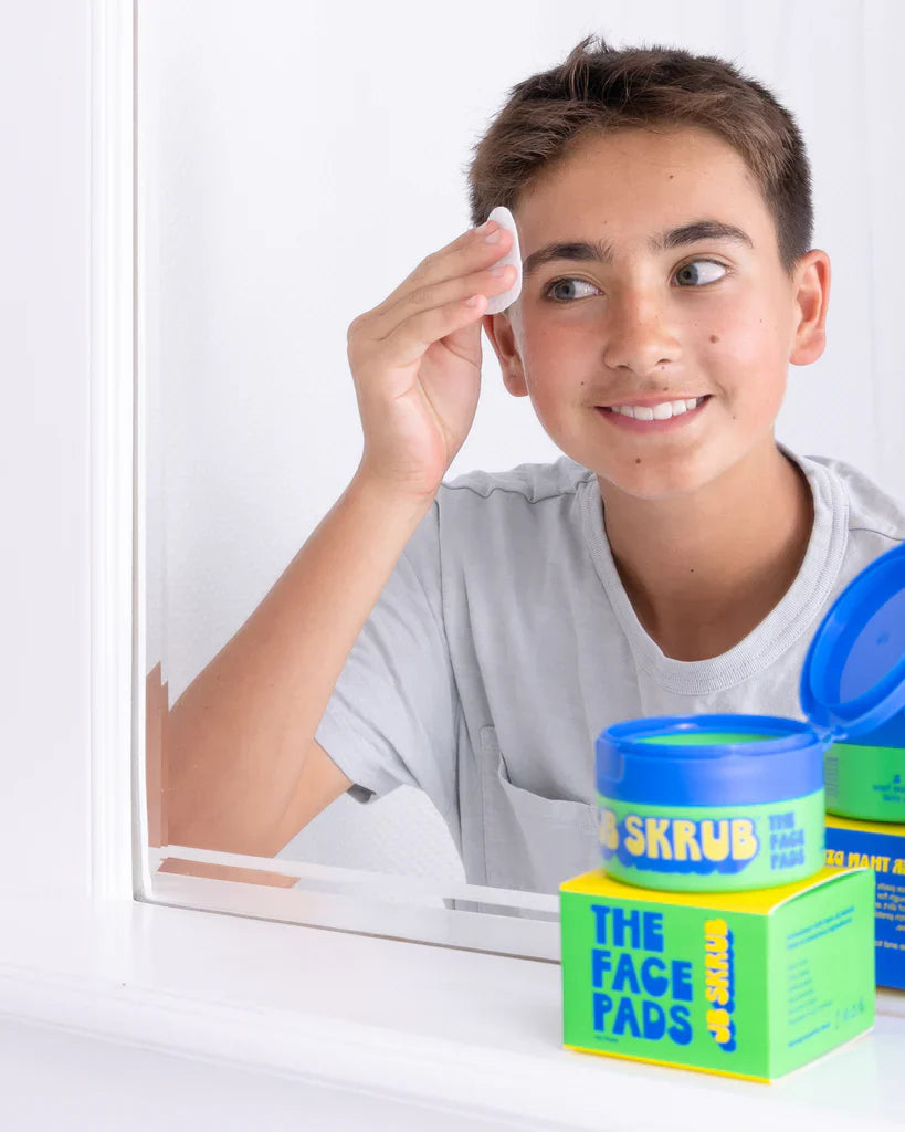 Boy using toner face pads in mirror